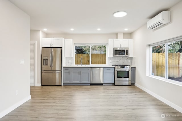 kitchen featuring a wall mounted AC, a wealth of natural light, light hardwood / wood-style flooring, and appliances with stainless steel finishes