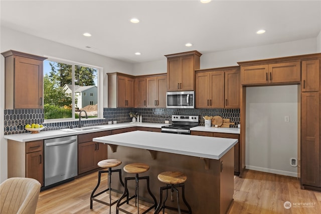 kitchen featuring a kitchen island, light wood-type flooring, backsplash, and appliances with stainless steel finishes