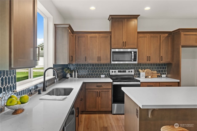 kitchen featuring sink, decorative backsplash, light wood-type flooring, and appliances with stainless steel finishes