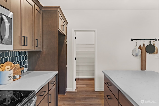 kitchen featuring backsplash, light stone counters, dark wood-type flooring, and stainless steel appliances