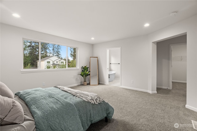 bedroom with carpet, connected bathroom, and a spacious closet