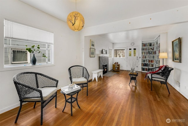 sitting room with wood-type flooring and a brick fireplace