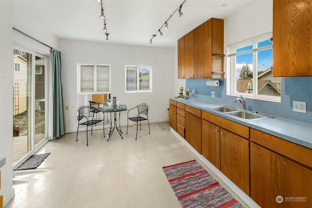 kitchen featuring light countertops, light floors, a sink, and brown cabinets