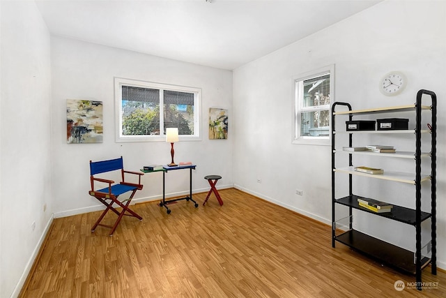 living area with a wealth of natural light, baseboards, and wood finished floors