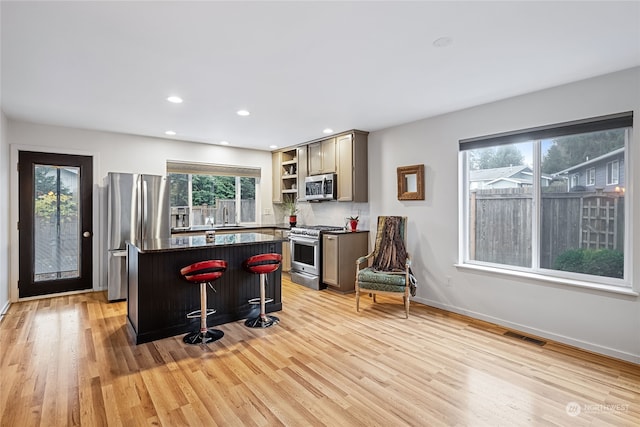 kitchen featuring a center island, sink, a wealth of natural light, appliances with stainless steel finishes, and a kitchen bar