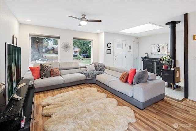 living room featuring a skylight, ceiling fan, and light hardwood / wood-style floors