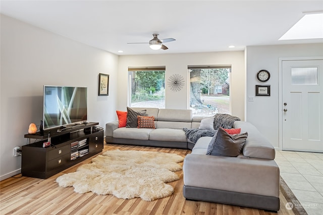 living room featuring a skylight, light hardwood / wood-style flooring, and ceiling fan