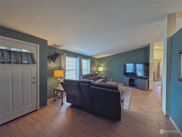 living room with wood-type flooring, a textured ceiling, and vaulted ceiling