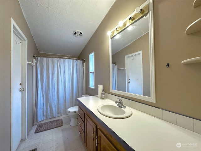 bathroom featuring a textured ceiling, vanity, lofted ceiling, and toilet