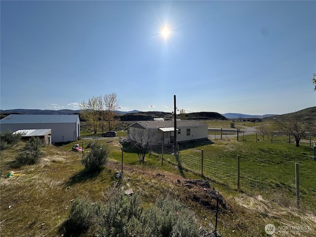 view of yard featuring fence, a rural view, and a mountain view