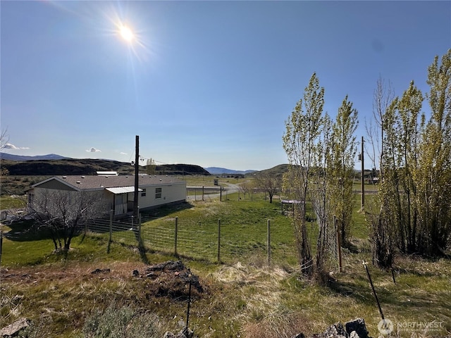 view of yard featuring fence, a rural view, and a mountain view