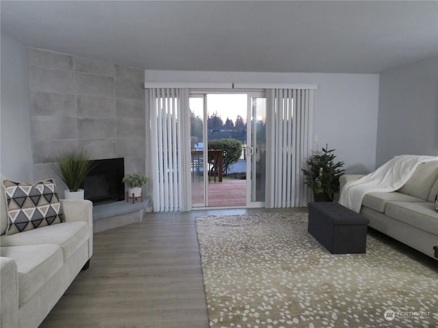 living room with a tile fireplace and hardwood / wood-style flooring