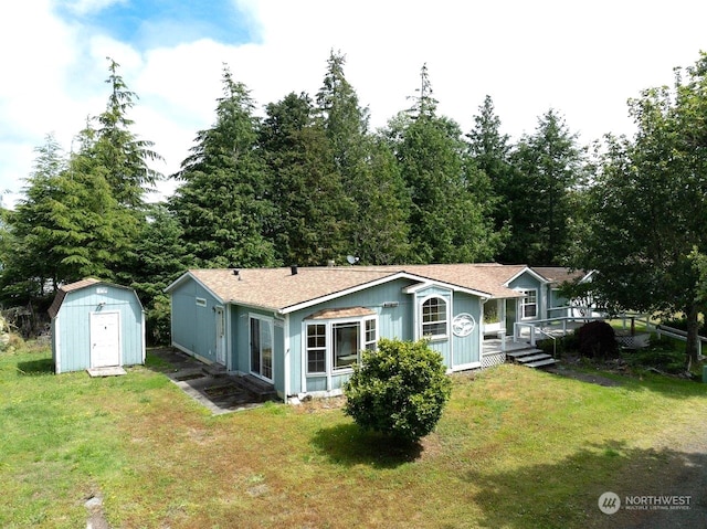 rear view of house featuring a yard, a shed, and a wooden deck