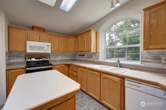 kitchen featuring plenty of natural light, tasteful backsplash, sink, and white appliances