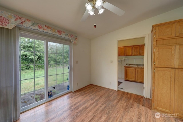 unfurnished dining area featuring light wood-type flooring, vaulted ceiling, and ceiling fan