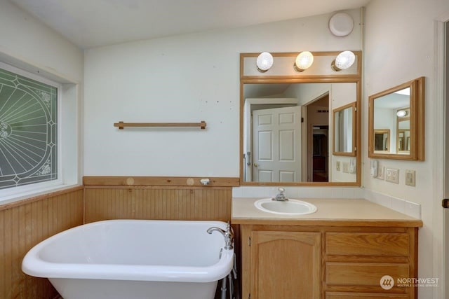 bathroom with a washtub, vanity, lofted ceiling, and wood walls