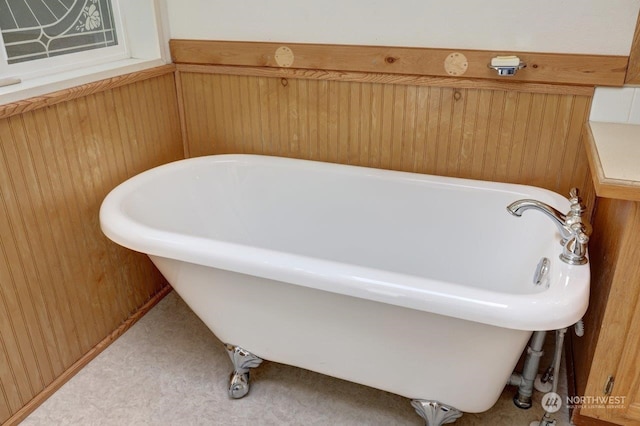 bathroom with wooden walls and a bath