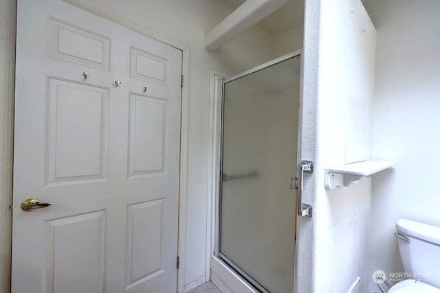 bathroom featuring toilet and a shower with shower door