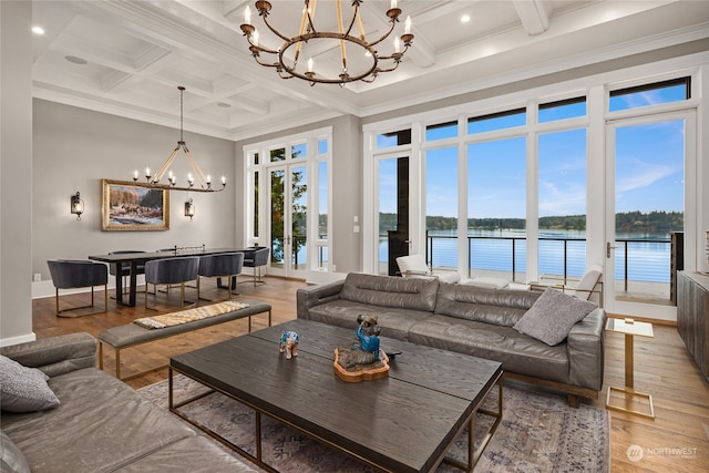 living room featuring a high ceiling, a water view, hardwood / wood-style flooring, and an inviting chandelier