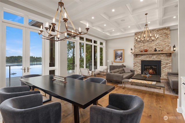 dining area with hardwood / wood-style flooring, beam ceiling, a water view, coffered ceiling, and a chandelier