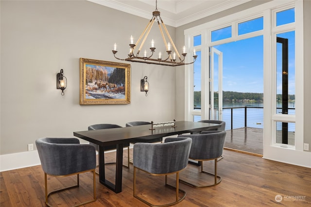 dining room featuring hardwood / wood-style flooring, crown molding, a water view, and a chandelier