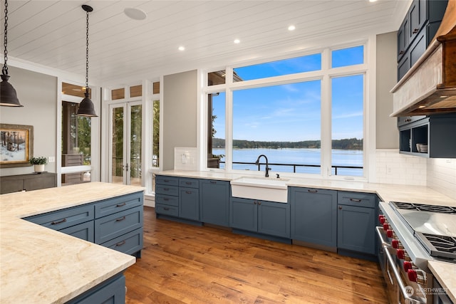 kitchen featuring pendant lighting, double oven range, hardwood / wood-style floors, a water view, and tasteful backsplash