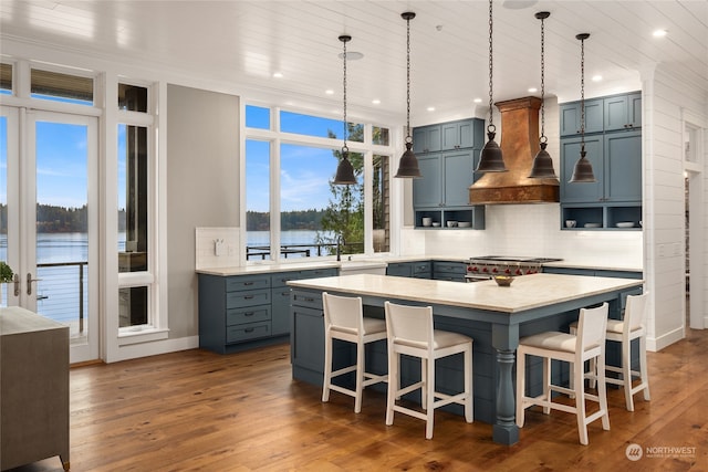 kitchen with tasteful backsplash, a kitchen bar, premium range hood, and a water view