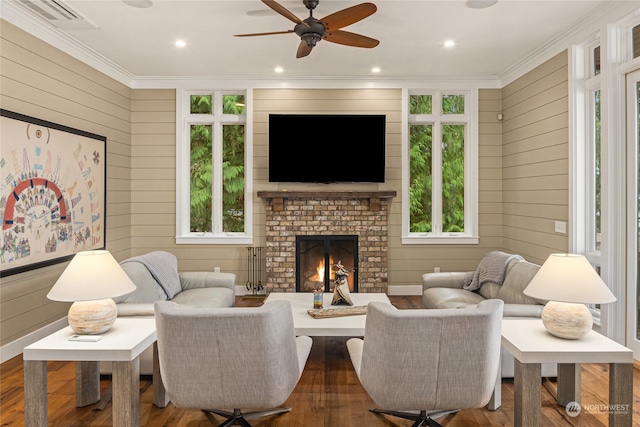 living room featuring crown molding, a healthy amount of sunlight, wood-type flooring, and a fireplace