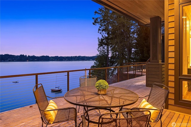 deck at dusk featuring a water view