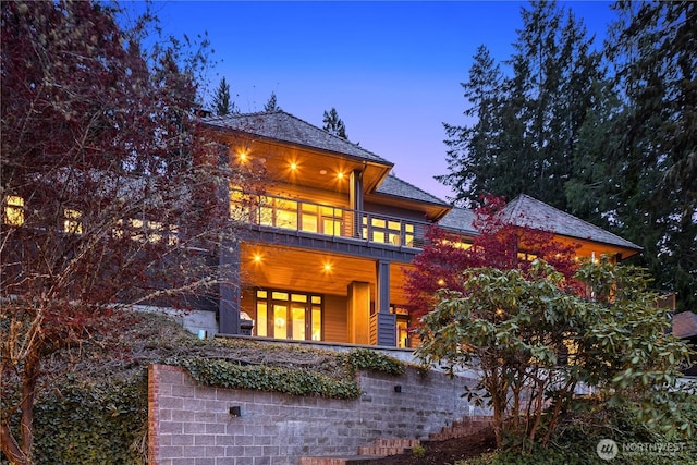 back house at dusk with a balcony