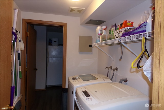 clothes washing area with dark hardwood / wood-style flooring and washing machine and clothes dryer