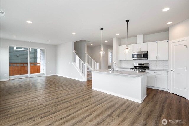 kitchen featuring decorative backsplash, appliances with stainless steel finishes, wood finished floors, white cabinets, and a sink