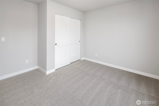 unfurnished bedroom with a closet, baseboards, and carpet