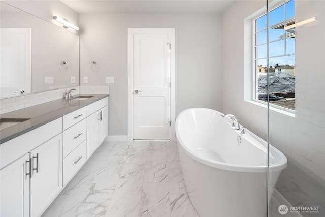 bathroom with a sink, a soaking tub, marble finish floor, and double vanity