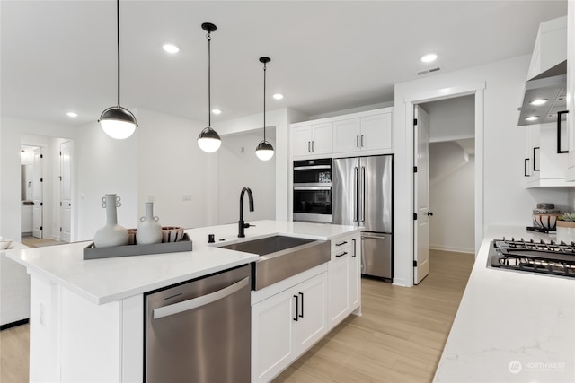 kitchen featuring white cabinets, sink, light hardwood / wood-style flooring, decorative light fixtures, and stainless steel appliances