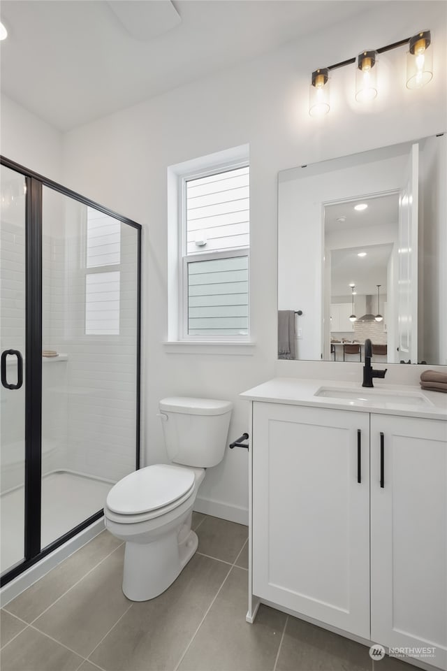 bathroom with tile patterned floors, toilet, vanity, and walk in shower