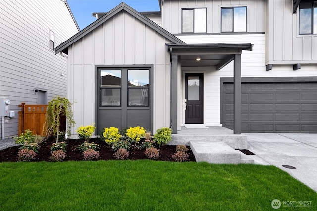 entrance to property featuring driveway, board and batten siding, an attached garage, a yard, and fence