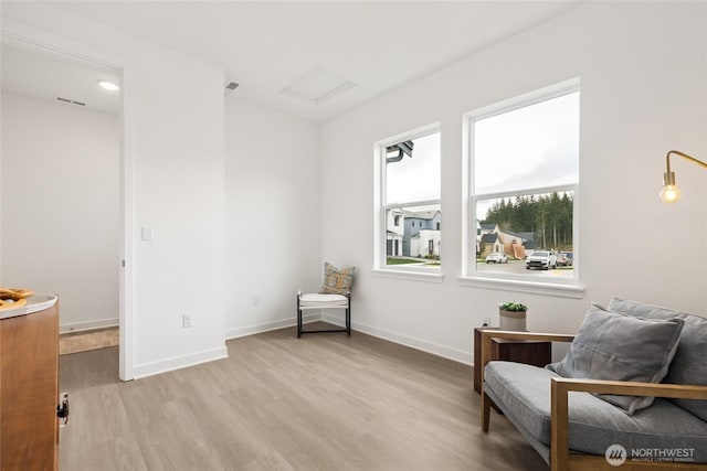 living area featuring attic access, light wood finished floors, baseboards, and visible vents