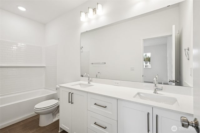 full bathroom with a sink, toilet, double vanity, and wood finished floors
