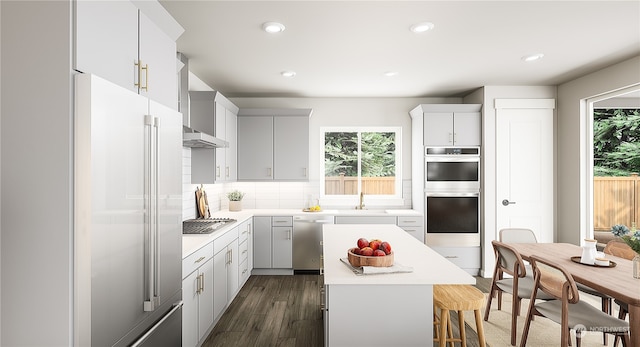 kitchen featuring appliances with stainless steel finishes, wall chimney exhaust hood, dark wood-type flooring, white cabinets, and a kitchen island