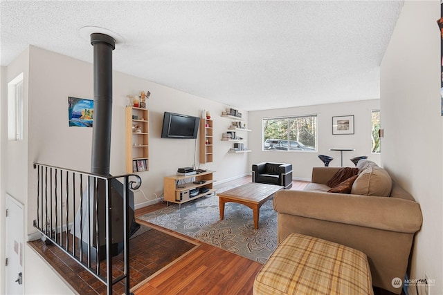 living room with hardwood / wood-style floors, a textured ceiling, and a wood stove