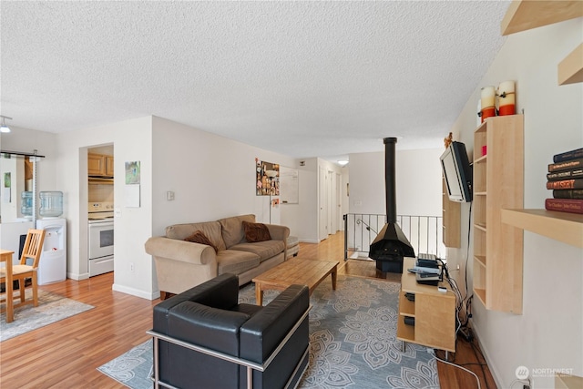 living room featuring hardwood / wood-style flooring, a wood stove, and a textured ceiling