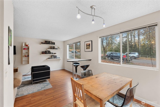 dining space with hardwood / wood-style floors and a textured ceiling