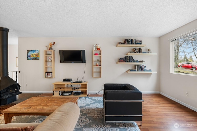 living room featuring a wood stove, a textured ceiling, and wood-type flooring