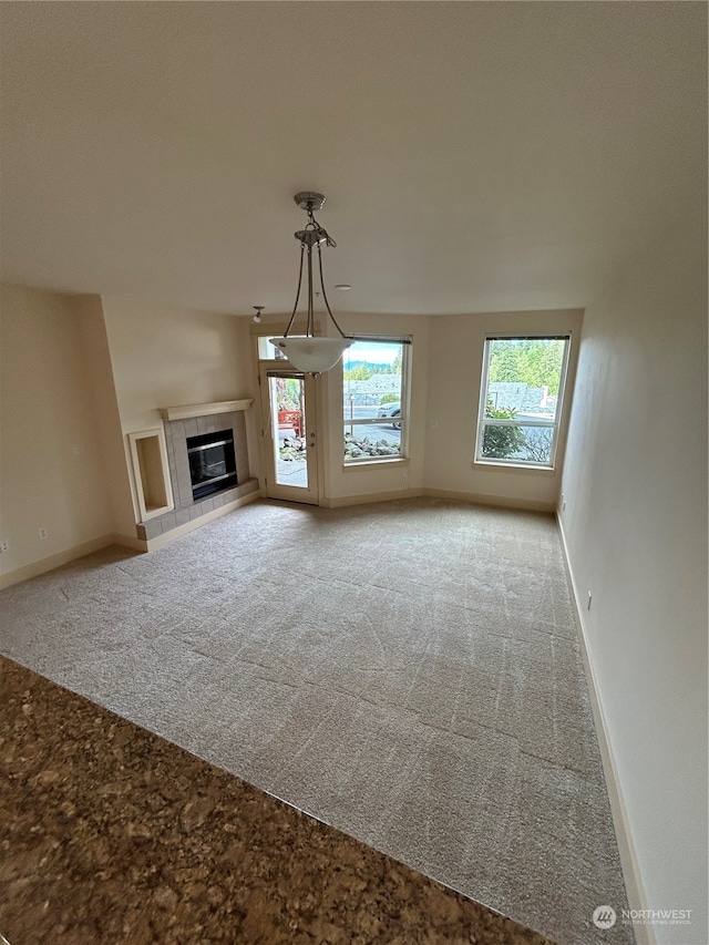 unfurnished living room featuring light carpet and a tiled fireplace