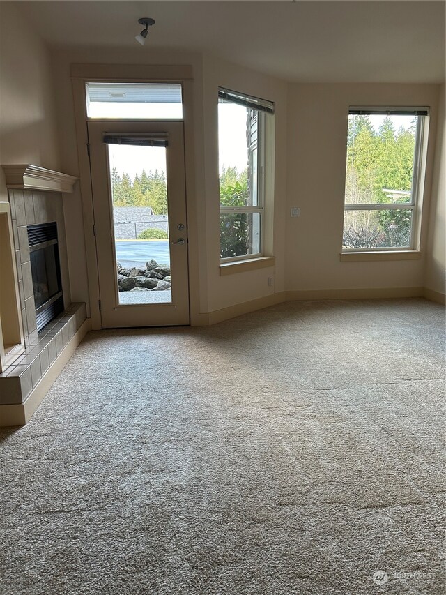 unfurnished living room with a fireplace, carpet, and a healthy amount of sunlight