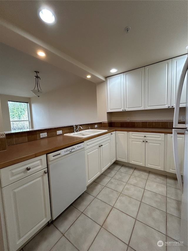 kitchen featuring light tile patterned floors, white dishwasher, white cabinetry, and sink