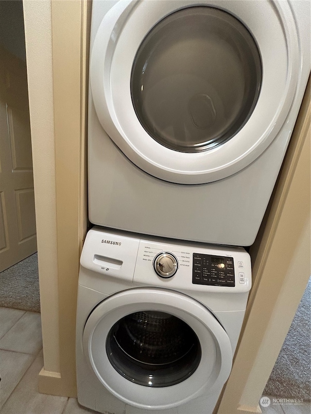 laundry room featuring light tile patterned flooring and stacked washer and clothes dryer