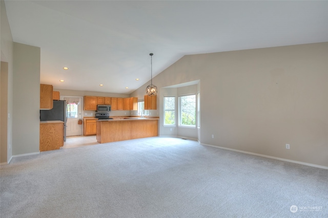 kitchen with decorative light fixtures, lofted ceiling, light carpet, and appliances with stainless steel finishes