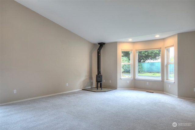 unfurnished living room featuring a wood stove and light colored carpet